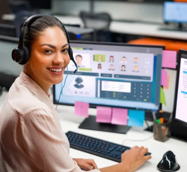 Happy female customer service agent and a computer in the background.