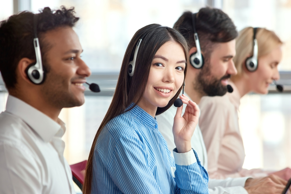 Group of diverse call center employees with Korean woman smiling at camera