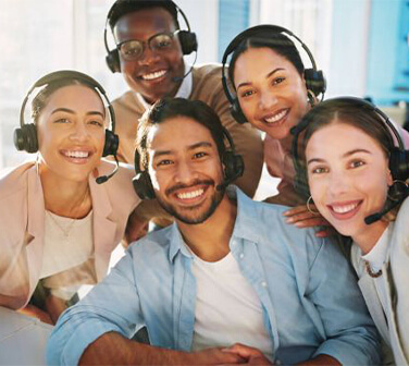Smiling customer service team taking a group selfie at a call center, illustrating career growth, teamwork, and workplace success.