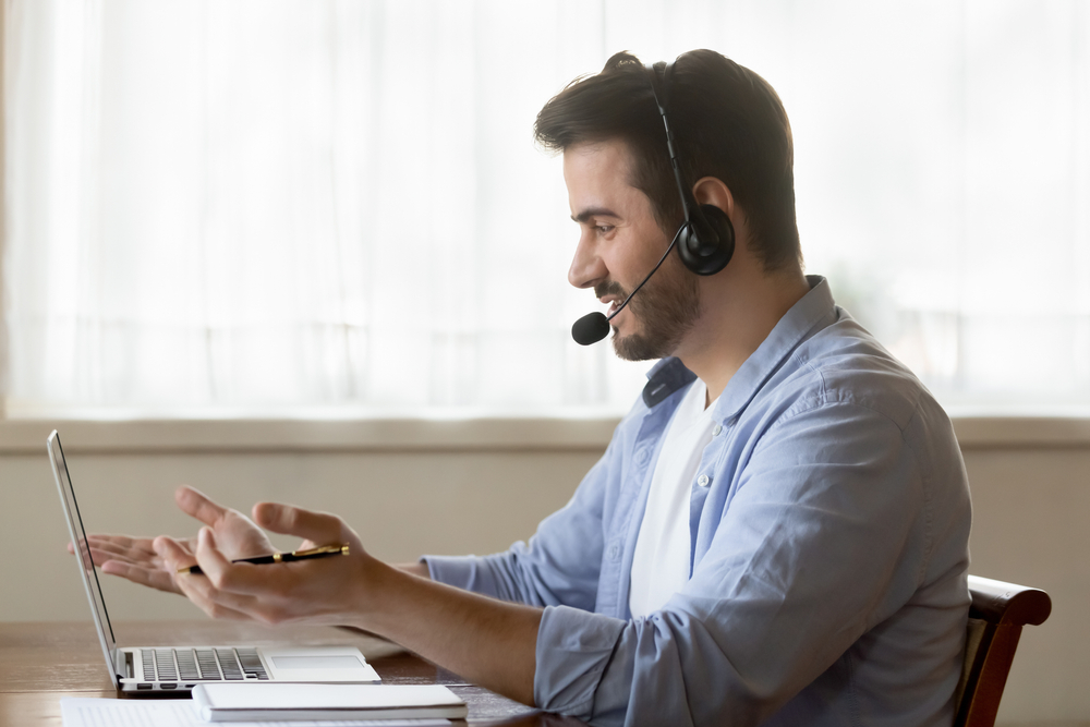 man with headset on talking to customer in front of laptop