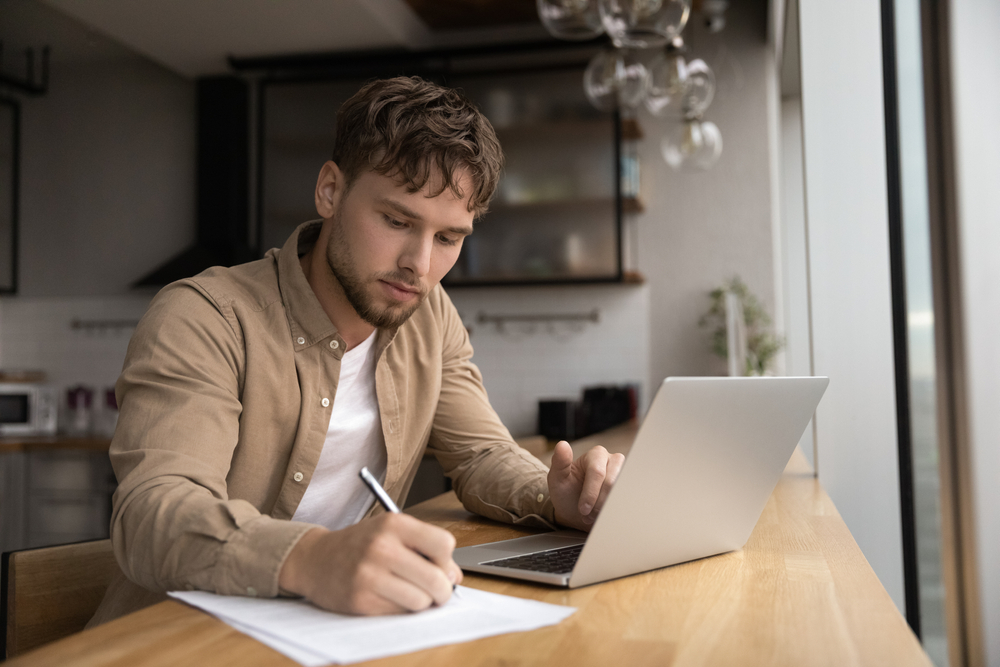 man making a list at work near laptop