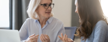 older business woman helps mentor younger business woman