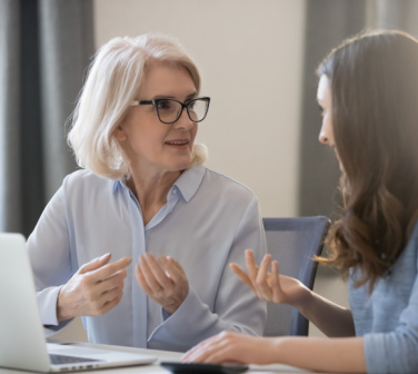 older business woman helps mentor younger business woman