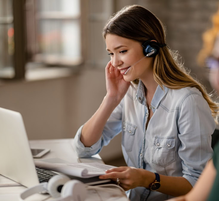 Smiling agent on a headset reviews notes while using small talk to create a friendly and effective customer call experience-1