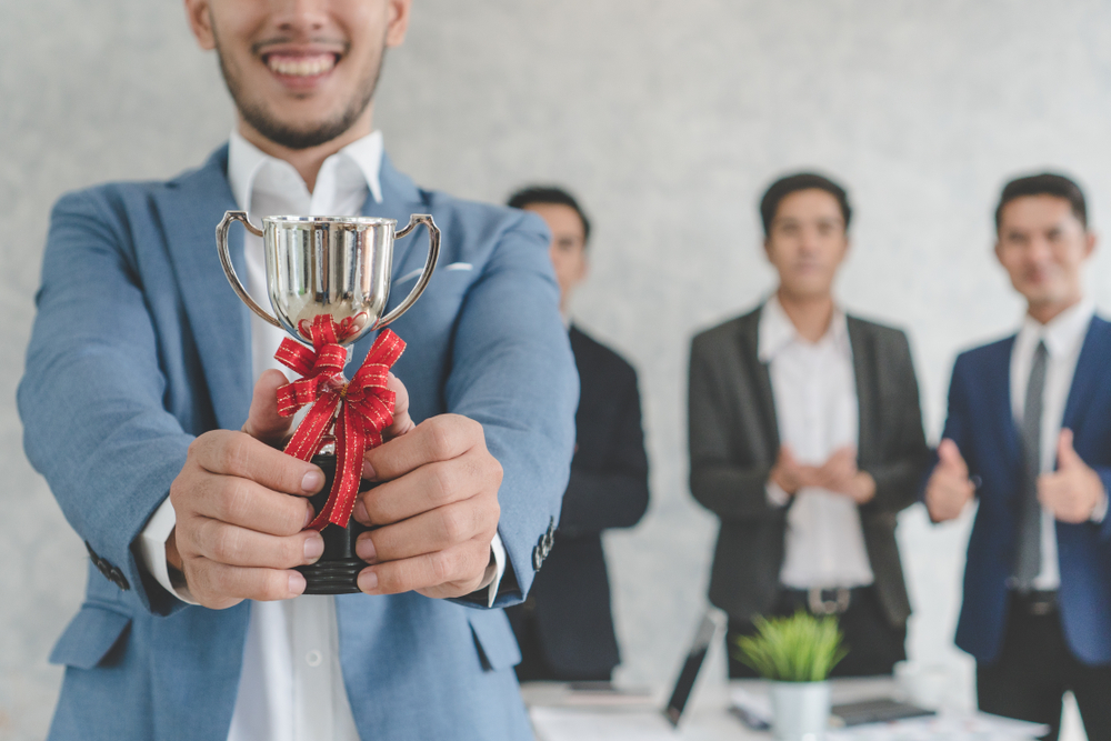 Happy employee holds a trophy for good work