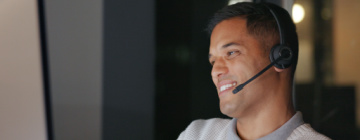 Hispanic call center agent smiles as he talks into his headset