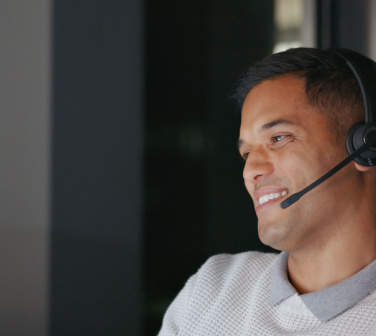 Hispanic call center agent smiles as he talks into his headset
