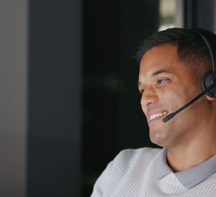 Hispanic call center agent smiles as he talks into his headset