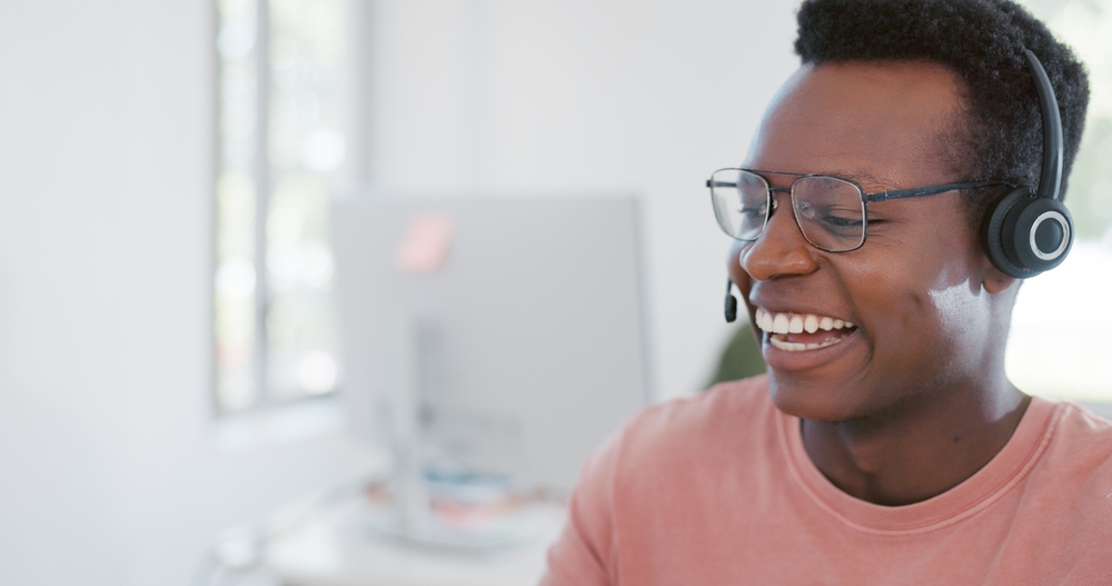 African American call center agent smiles as he talks to a customer