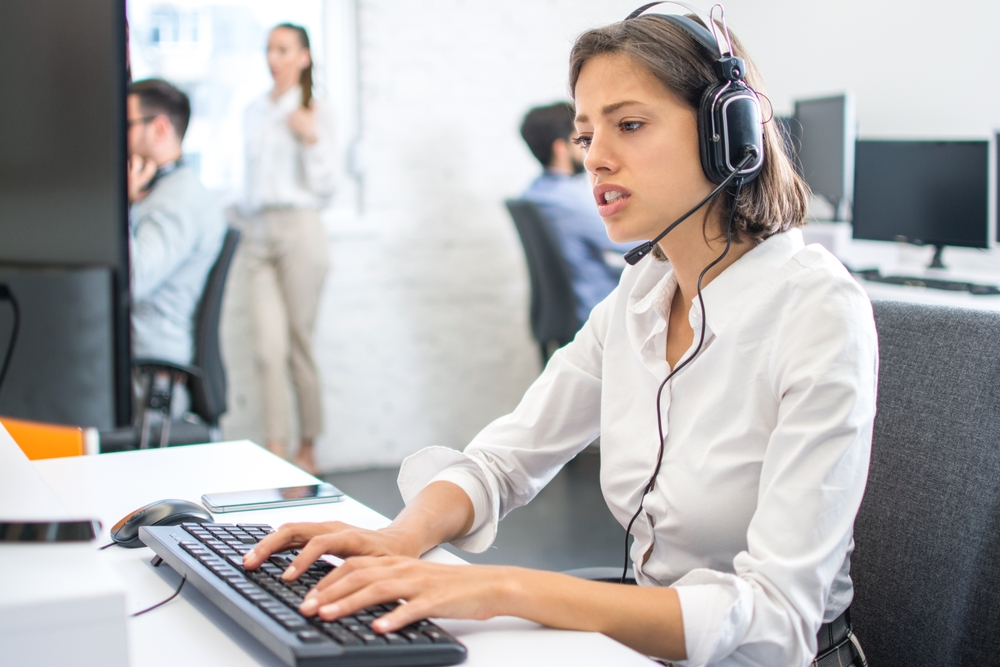 Young woman call center employee working with customer on phone wearing headset