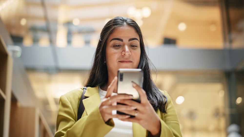 Hispanic employee checks her phone while similing