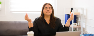 Young Hispanic woman strikes yoga pose at desk