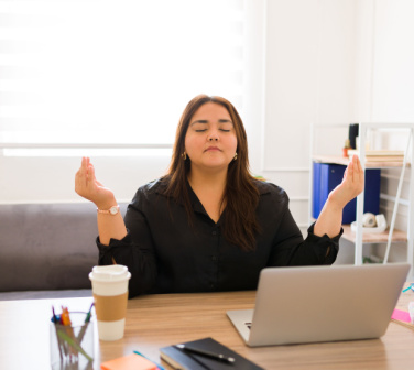 Young Hispanic woman strikes yoga pose at desk