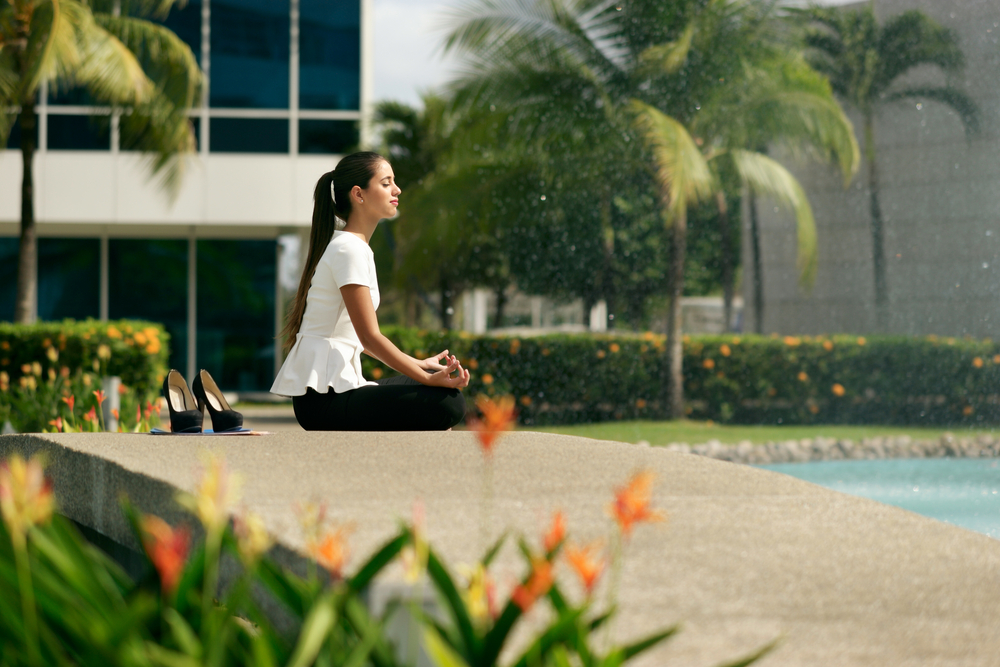 Young woman employee takes a break to do some yoga outside the office
