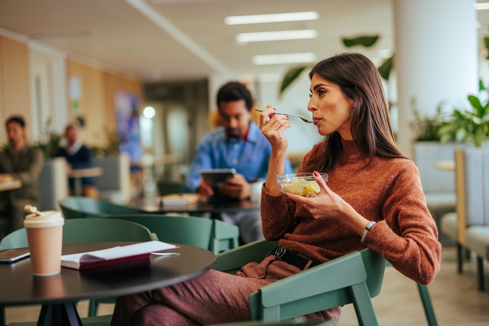 Young woman enjoys a healthy lunch in the company cafeteria - working at Seguros Confie