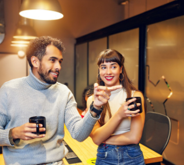Two colleagues talk together with morning coffee - best call center jobs in Tijuana
