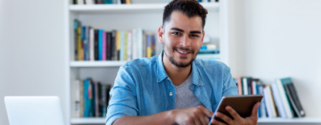 Young smiling Latin man uses innovative technology to look for a job - call center positions in Tijuana