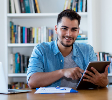 Young smiling Latin man uses innovative technology to look for a job - call center positions in Tijuana