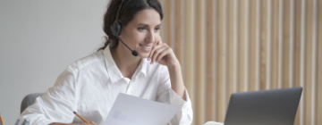 Smiling Hispanic woman with headset being productive at work - call center jobs in Tijuana