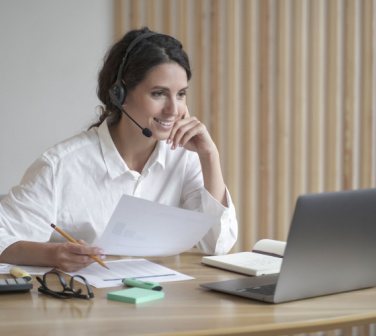 Smiling Hispanic woman with headset being productive at work - call center jobs in Tijuana
