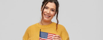 Woman holding a U.S. flag and smiling, symbolizing bilingual speakers connected to American culture and language-1