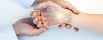 A medical professional examines a hand with graphics to show carpal tunnel - best call center in Tijuana.