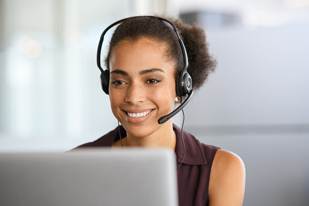 Young mixed race woman wearing headset talking to a customer - best call center jobs in Tijuana.