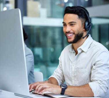 Smiling Hispanic man answers a call wearing a headset at a call center - best call center jobs in Tijuana.