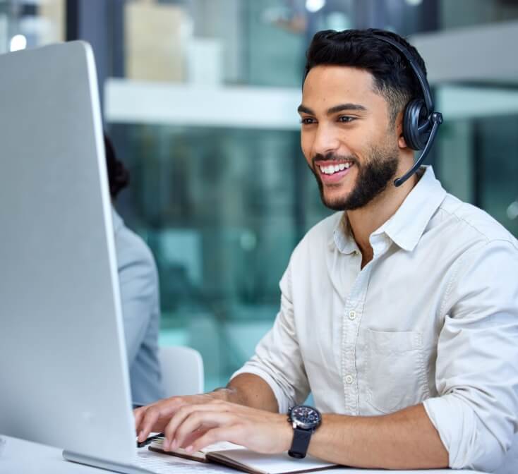 Smiling Hispanic man answers a call wearing a headset at a call center - best call center jobs in Tijuana.