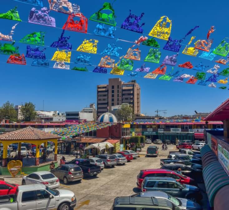 View of a colorful market in Tijuana with a large building in the background - Best Call Center in Tijuana.