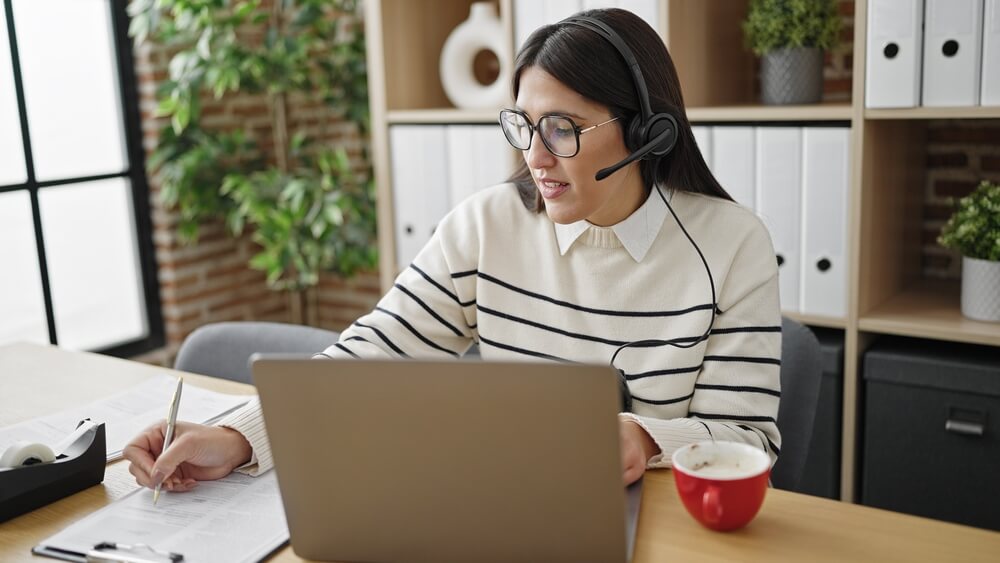 Call Center agent working in her computer with headphones with a cup of coffee