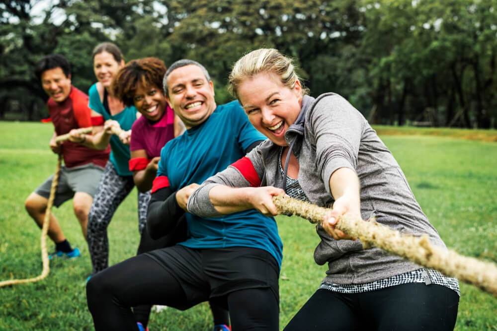 Team of co-workers plays tug-of-war for motivation.