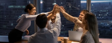 Sales team giving high fives after a successful motivation by leader.