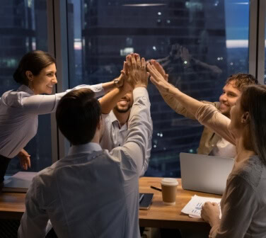 Sales team giving high fives after a successful motivation by leader.