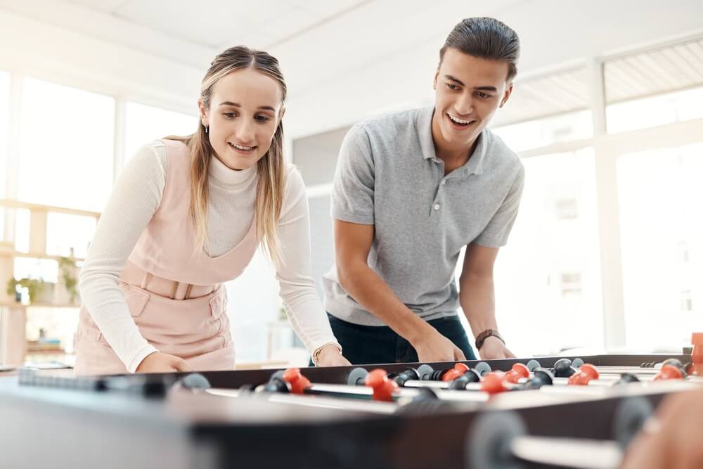 Young female and male workers at call center take a break from work to play foodball.