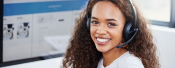 Smiling customer service call center work with her headphones on looking at camera.