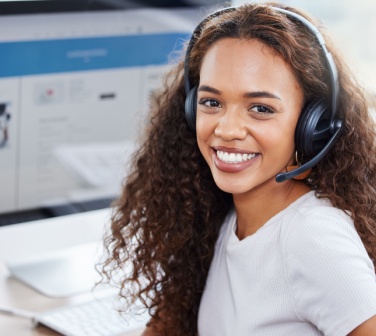Smiling customer service call center work with her headphones on looking at camera.