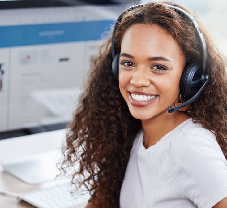 Smiling customer service call center work with her headphones on looking at camera.