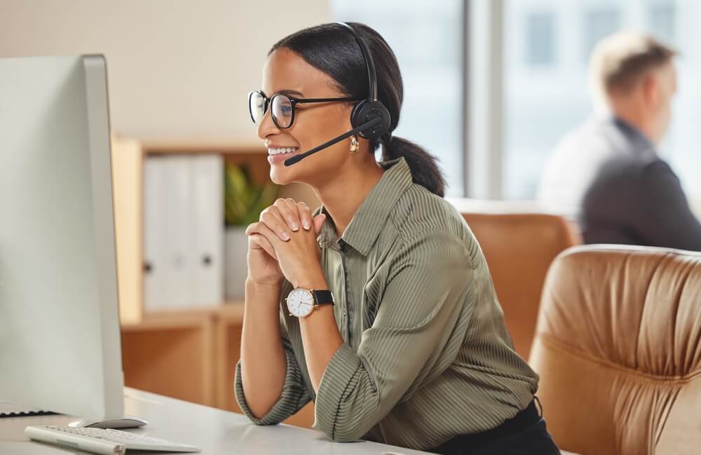 Smiling call center agent works with a customer on the phone.