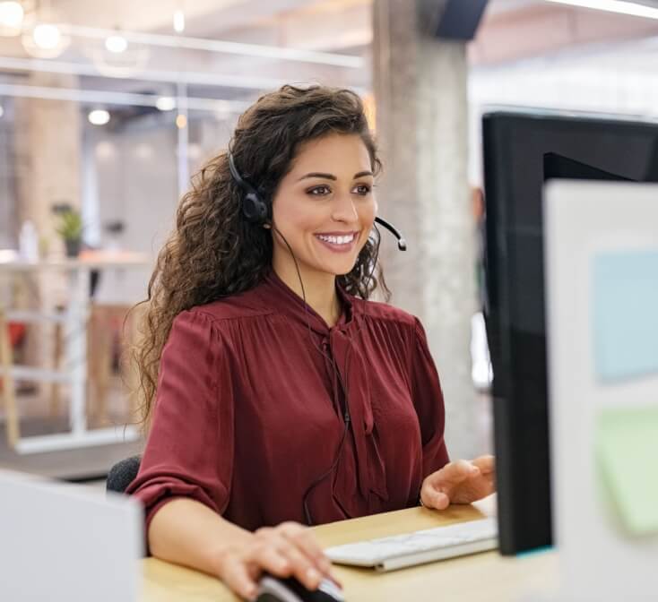 A female call center agent smiling while working, answering calls relaxed due to practicing self-motivation strategies for call center agents - Seguros Confie, the Coolest Call Center.