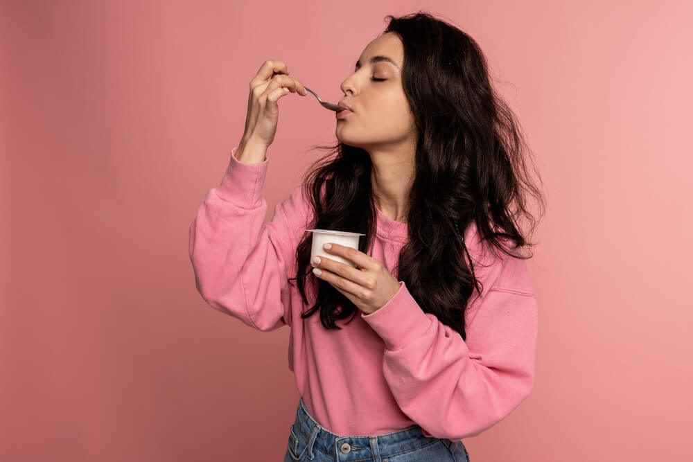 Young woman eats a healthy snack to combat stress at work - best call center jobs in Tijuana.