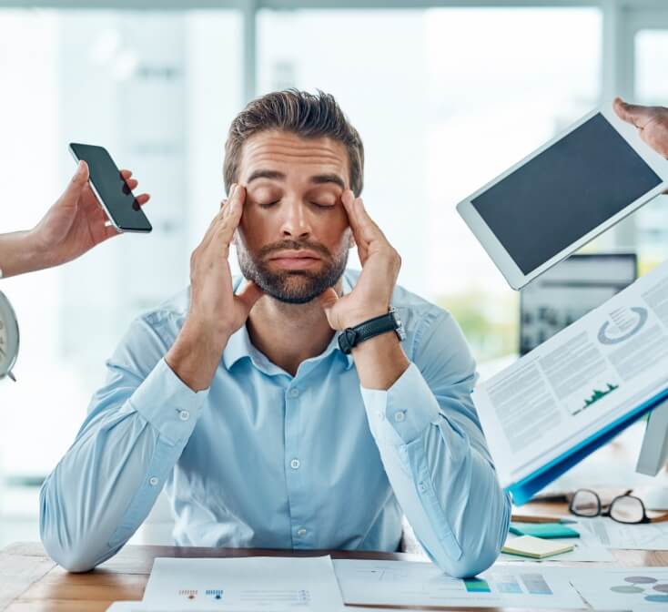 Young man has a headache as stress mounts by coworkers handing items to him - best call center job in Tijuana.