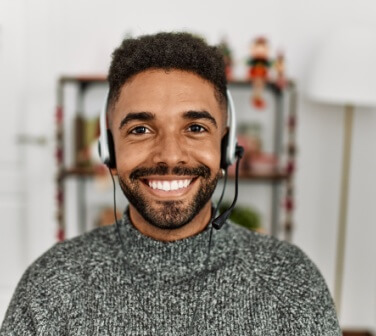Smiling man faces camera with headset on, taking and making calls - best call center in Tijuana.