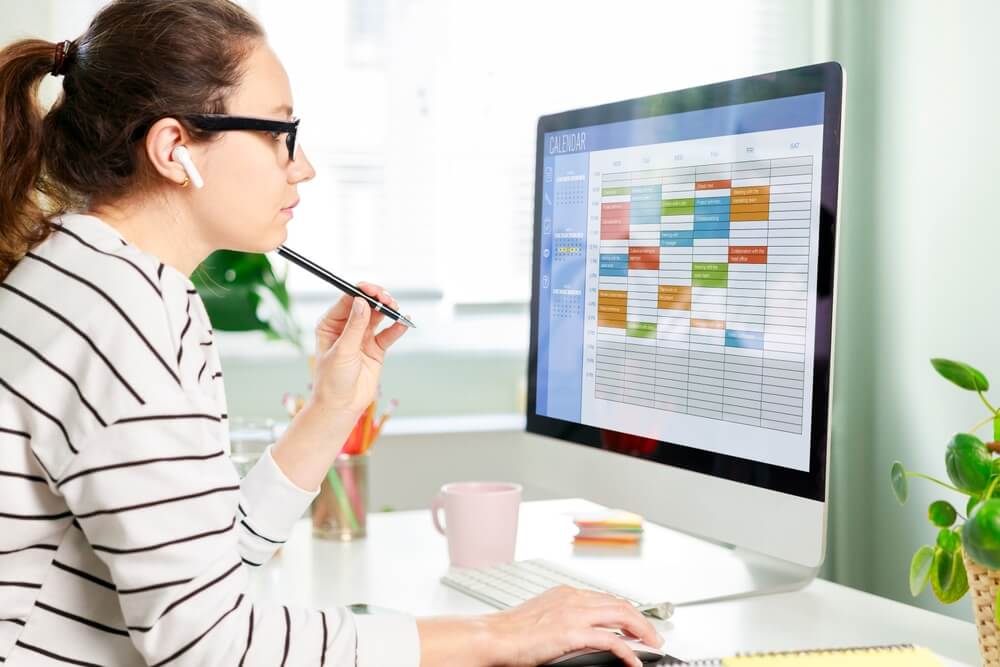 Freelancer woman using calendar on computer to improve time management, plan appointments, events, tasks and meetings efficiently, improve productivity, organize week day and work hours.