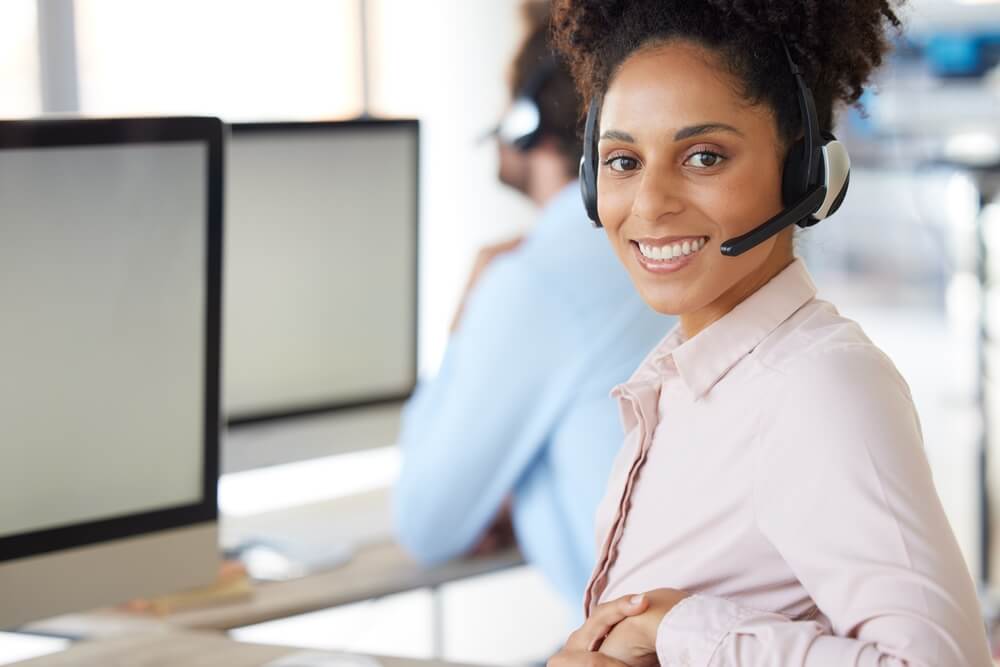 Smiling female call center agent looks at camera - best call center job in Tijuana.