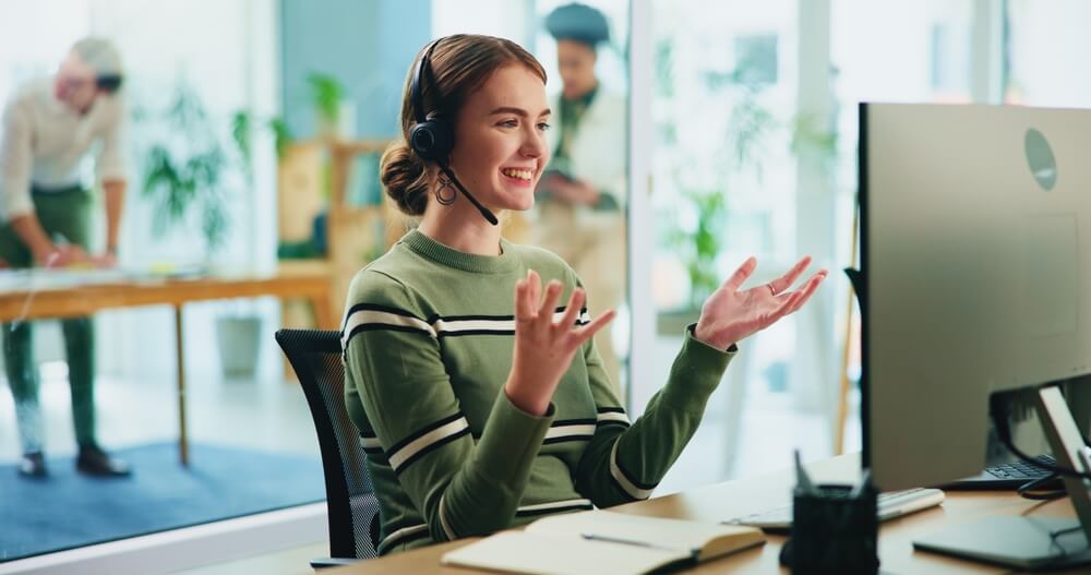 A young female call center worker smiling and talking to a customer on the phone - best call center jobs in Tijuana.