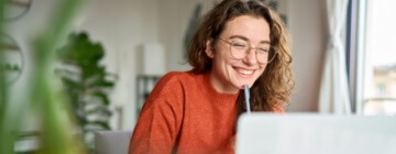 Young girl smiles at the laptop while working customer service from home - best call center in Tijuana.