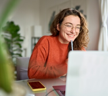 Young girl smiles at the laptop while working customer service from home - best call center in Tijuana.