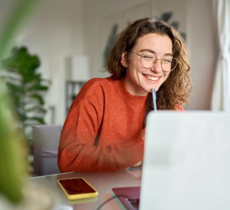Young girl smiles at the laptop while working customer service from home - best call center in Tijuana.