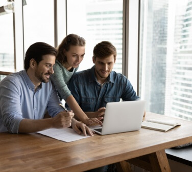 Two male and one female call center colleagues help each other master new skills - best call center jobs in Tijuana.